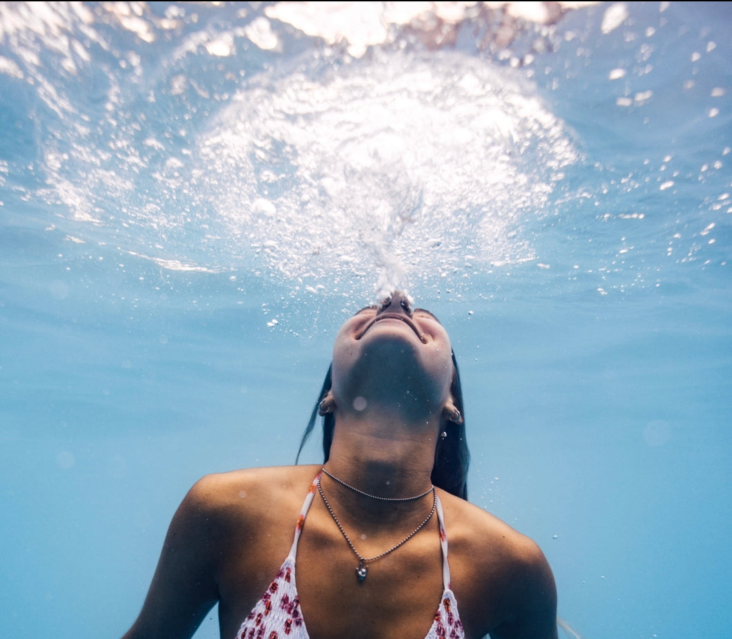 Girl wearing ILY Necklace while free diving in the ocean